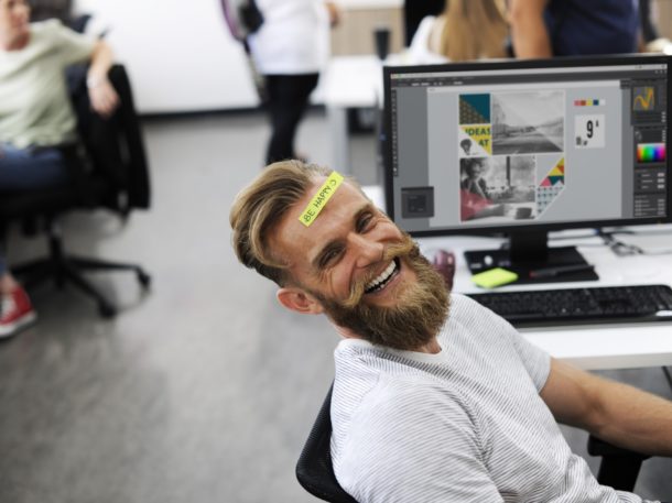 Man smiling in the workplace with a sticker on his head