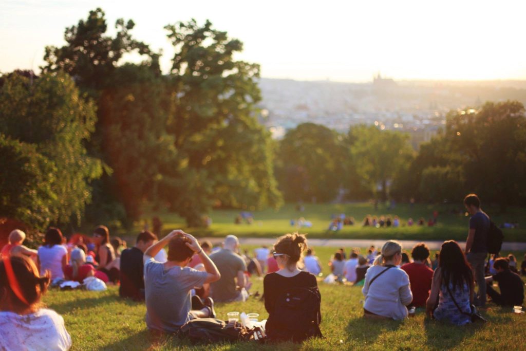 People sitting in a field as the sun goes down